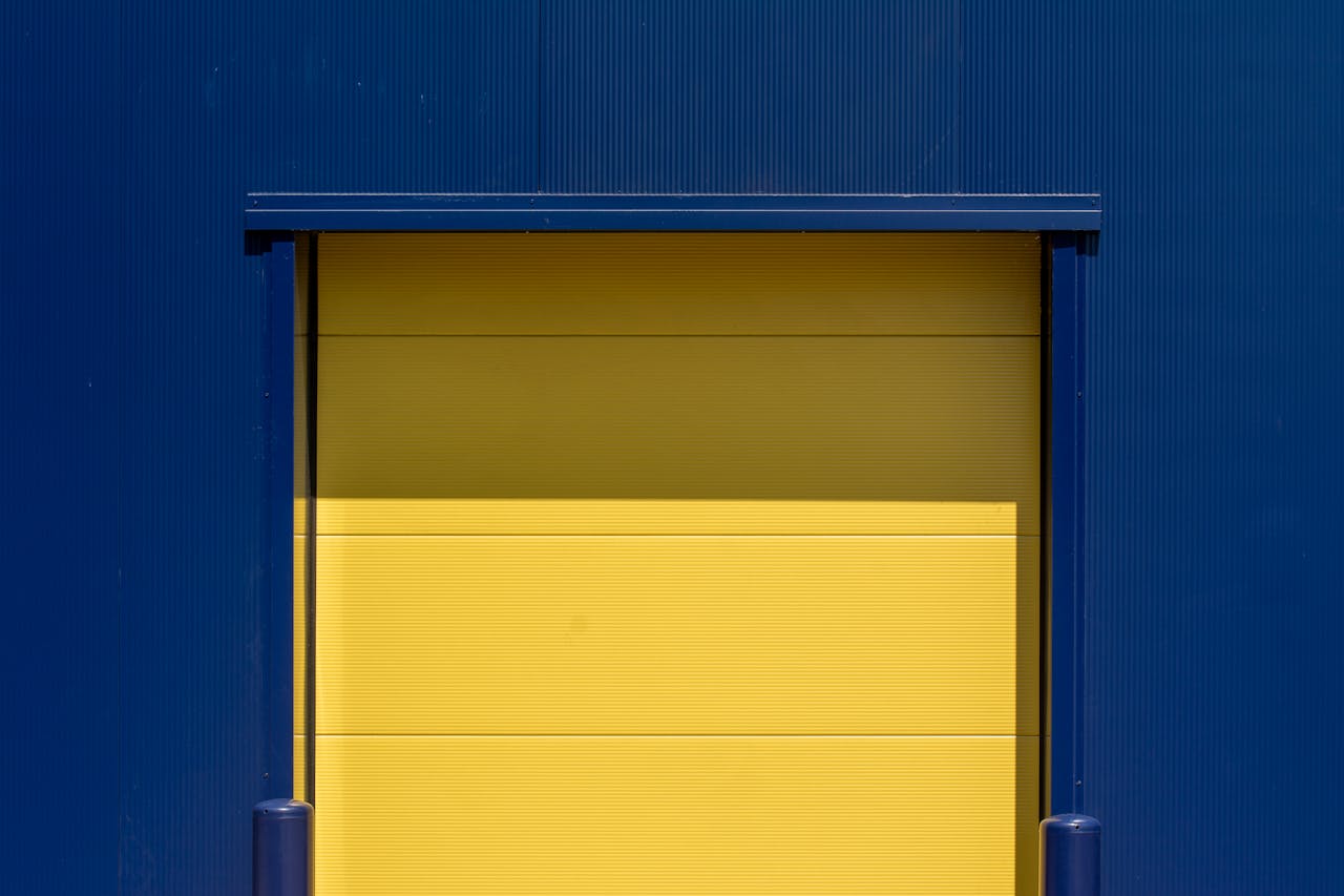 Vibrant yellow industrial door set against a blue metal wall, showcasing modern urban design.